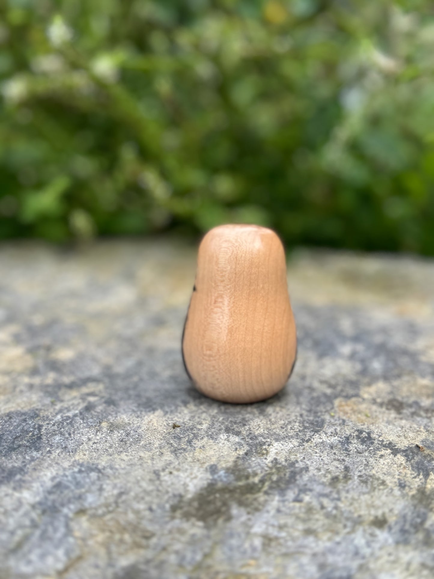 Daruma en bois blanc peint noir et rouge avec calligraphie vue de dos
