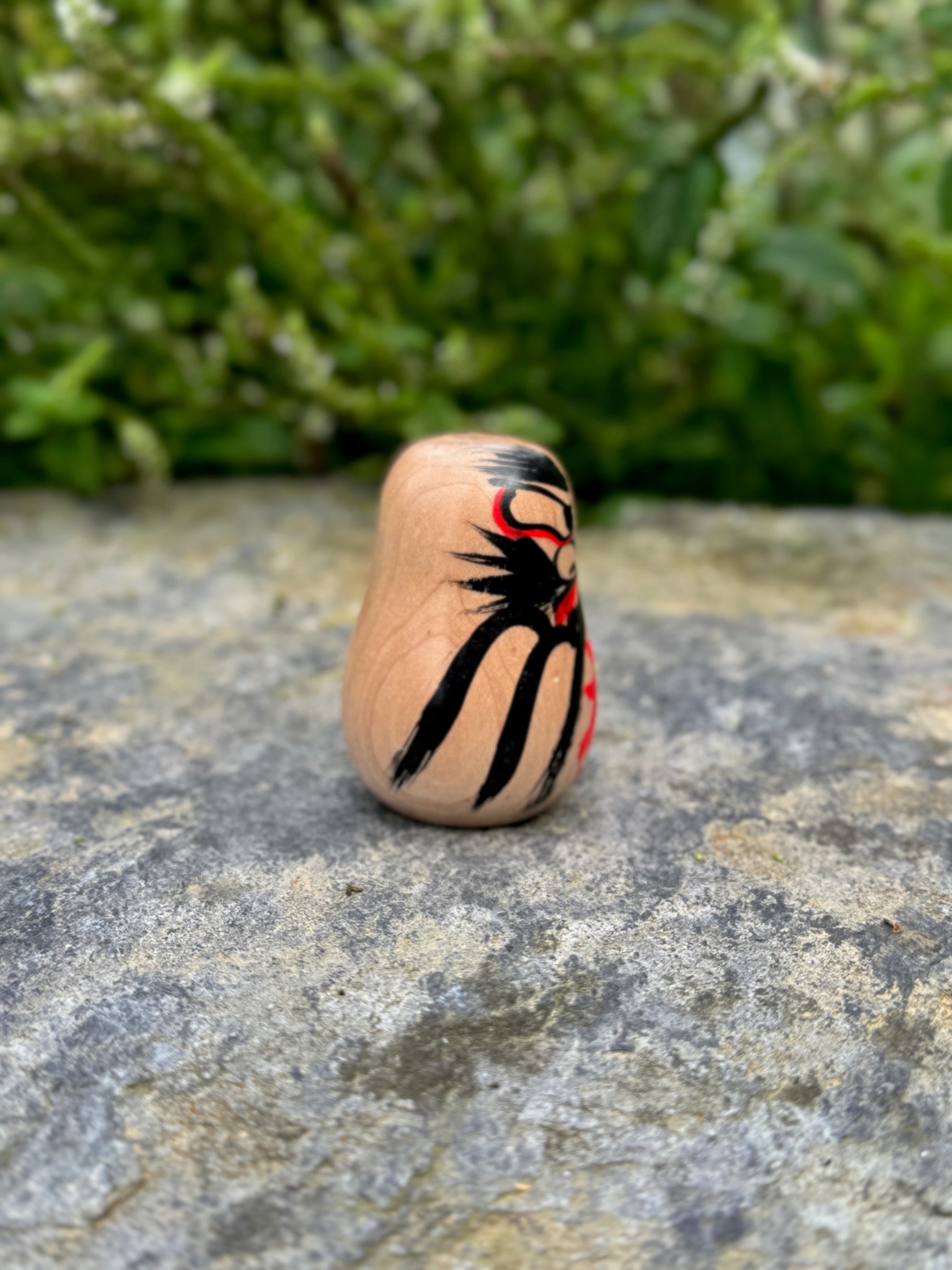 Daruma en bois blanc peint noir et rouge avec calligraphie profil droit