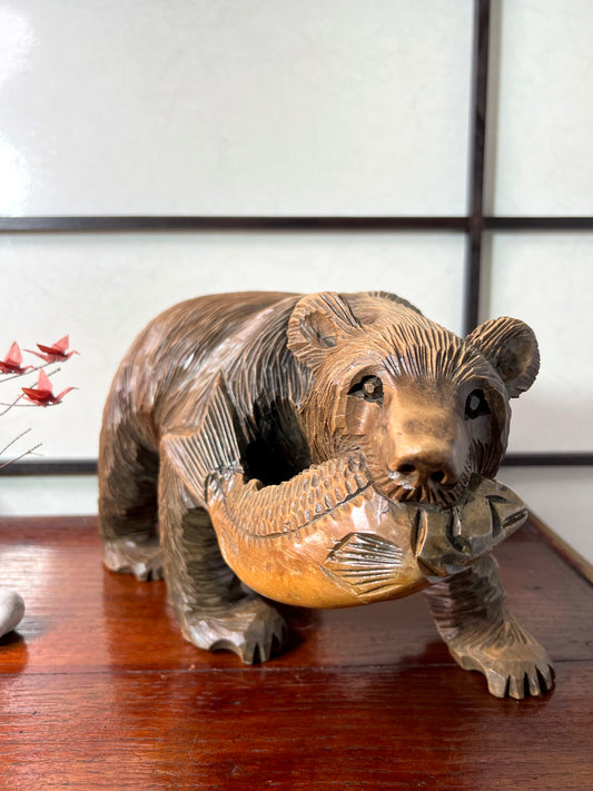 sculpture en bois japonaise d'ours avec un saumon dans la gueule, vu de face