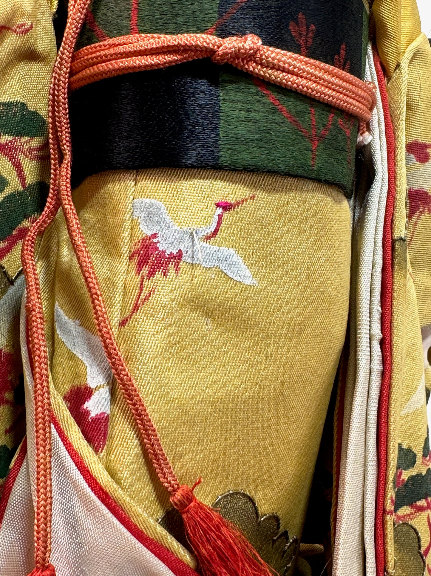 poupée japonaise ancienne en kimono jaune à motif de grues et massif de pin, gros plan sur les grues