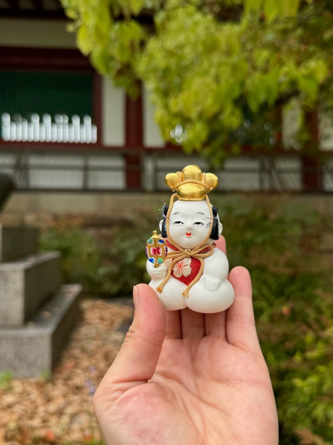 Poupée japonaise traditionnelle gosho, petit garçon potelé, tient éventail dans sa main et chapeau doré sur sa tête.